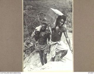 YAULA, NEW GUINEA. 1944-04-11. AIYUP, A MARKHAM BOY ( ), AND DIDA, A WEWAK BOY ( ), CARRYING SUPPLIES DURING THE ADVANCE OF THE 57/60TH INFANTRY BATTALION TO BOGADJIM