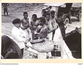 TOBOI WHARF, NEW BRITAIN. 1945-09-16. NATIVES AT THE WHARF WELCOMING PRIESTS AND SISTERS WHO HAVE BEEN LIBERATED FROM INTERNMENT AT RAMALE MISSION AND BROUGHT TO RABAUL FOR MEDICAL CARE