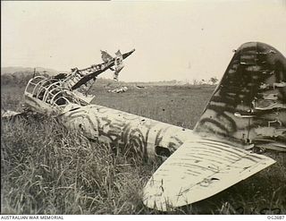 BUT AREA, DAGUA, NORTH EAST NEW GUINEA. C. 1945-04. BEHIND A BROKEN JAPANESE KAWASAKI KI-48, ARMY TYPE 99 TWIN-ENGINED LIGHT BOMBER AIRCRAFT, ALLIED CODE NAME LILY, ARE SOME OF THE 102 WRECKED ..