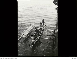 Los Negros Island, Admiralty Group. c. 1943. Four natives in an outrigger canoe alongside HMAS Broome