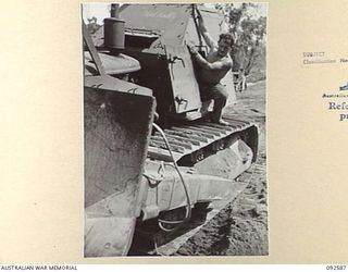 BOUGAINVILLE. 1945-05-26. SAPPER G.E. O'KEEFE, 6 MECHANICAL EQUIPMENT COMPANY (AUSTRALIAN IMPERIAL FORCE), CLIMBING OUT OF THE ARMOURED TURRET OF A BULLDOZER ON THE BUIN ROAD. THE BULLDOZER WAS TO ..