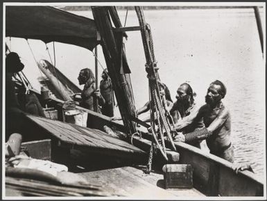 Five Papuan men standing alongside a boat, Papua New Guinea, ca. 1920s / Frank Hurley