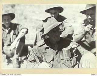 BOGADJIM, NEW GUINEA. 1944-04-26. VX81112 LIEUTENANT G. H. ATKINSON (1), WHO LED A PATROL FROM C COMPANY, 57/60TH INFANTRY BATTALION, HAVING COFFEE WITH MEMBERS OF HIS PATROL AT A SALVATION ARMY ..