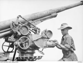 HANSA BAY, NEW GUINEA. 1944-09-07. QX34332 LANCE CORPORAL R. CURRELL, 5TH DIVISION SALVAGE UNIT CHECKING A JAPANESE 75MM MOBILE ANTI-AIRCRAFT GUN, TYPE 88. IT IS FITTED WITH THE MATCH POINTER DIALS ..