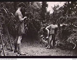 BULLDOG-WAU ROAD, NEW GUINEA, 1943-07-14. ENGINEERS OF HEADQUARTERS, ROYAL AUSTRALIAN ENGINEERS, 11TH AUSTRALIAN DIVISION, CONSTRUCTING THE ROAD WITH HAND TOOLS AT THE 24 1/2 MILE POINT