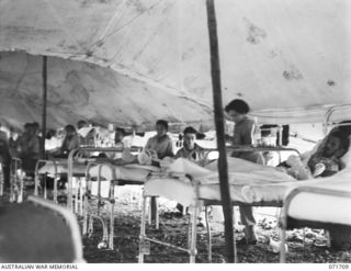 LAE, NEW GUINEA, 1944-03-25. THE INTERIOR OF WARD 1, SURGICAL WARD, 2/7TH GENERAL HOSPITAL. SHOWN ARE: PRIVATE COX (1); SFX10150 SISTER M. W. COOPER, AUSTRALIAN ARMY NURSING SERVICE (AANS) (2); AN ..