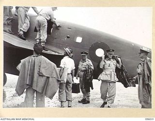 PALMALMAL AIRSTRIP, NEW BRITAIN. 1945-09-04. LIEUTENANT GENERAL V.A.H. STURDEE, GENERAL OFFICER COMMANDING FIRST ARMY (2), PUTTING ON A GAS CAPE SHORTLY AFTER ARRIVING FROM LAE BY RAAF BEAUFORT ..