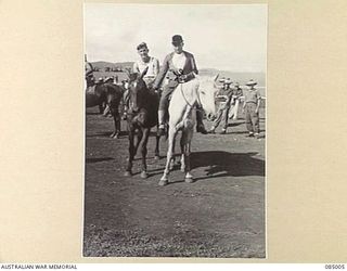 KAIRI, ATHERTON TABLELAND, QLD. 1944-12-25. PRIVATE H.W. REED, (1), WHO RODE SILVER DASH TO VICTORY IN THE FINISTERRE STAKES, IS LED FROM THE COURSE BY THE CLERK OF COURSE, LIEUTENANT J.W. WAITES, ..