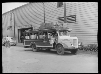 Street scene including Etablissements Donald Tahiti building and passengers in a public bus, Papeete, Tahiti