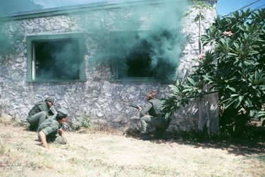 Two Air Force security policemen, with a U.S. Marine Corps instructor observing, prepare to enter a building occupied by a group of "terrorists" holding hostages. The policemen are taking part in an anti-terrorist training exercise being conducted by the 1st marine Brigade School