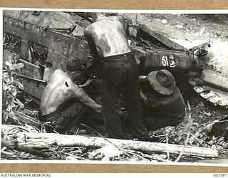 FINSCHHAFEN AREA, NEW GUINEA.  NX140713 STAFF SERGEANT J. E. SAUNDERS AND MEMBERS OF THE 1ST TANK GROUP BATTALION WORKSHOP CANNIBALISING A DAMAGED TANK FOR PARTS