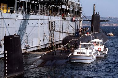 The Fulton-class submarine tender USS ORION (AS 18) services a submarine. The ORION is berthed at the Italian island of Santo Stefano, located between the Sandinian coastal town of Palau and the island of La Maddalena