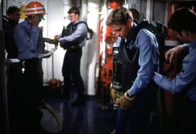 Members of a firefighting team put on oxygen breathing apparatuses in preparation for a drill aboard the amphibious assault ship USS GUAM (LPH 9)