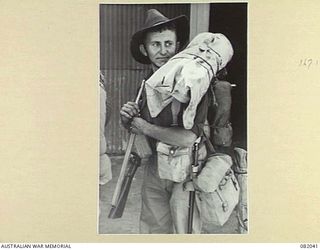 CAIRNS, QLD. 1944-10-30. PRIVATE S.S. WEBSTER, A COMPANY, 2/4 INFANTRY BATTALION, WAITING HIS TURN TO MOVE UP THE GANG PLANK DURING EMBARKATION FOR NEW GUINEA ABOARD THE TROOPSHIP USS MEXICO