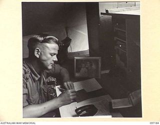 CAPE WOM, NEW GUINEA. 1945-09-27. CAPTAIN J.W. SINCLAIR, OFFICER COMMANDING 110 BRIGADE ORDNANCE FIELD PARK, AT WORK IN HIS OFFICE