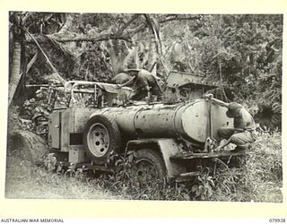 DAGUA, NEW GUINEA. 1945-03-25. NX135588 PRIVATE G.E. PORTER (1), AND VX15648 PTE M. LISTER (2), EXAMINE AN ABANDONED JAPANESE WATER CART AT THE AIRSTRIP