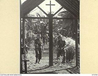 Karkar Island, New Guinea. 1944-06-03. VX122015 Corporal Kevin Joseph Condon (1) and VX118725 Private J. J. Suckling (2), two members of the 37/52nd Infantry Battalion, at the entrance to the ..