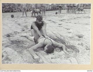 TOROKINA, BOUGAINVILLE, 1945-07-08. AN ROYAL AUSTRALIAN NAVY COMPETITOR APPLYING ARTIFICIAL RESPIRATION TO A PATIENT DURING THE RESCUE DISPLAY AT THE CHAMPIONSHIP SURF CARNIVAL HELD BY SOLOMON ..