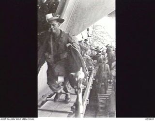 WEWAK HARBOUR, NEW GUINEA, 1945-12-13. APPROXIMATELY 2,200 MEMBERS OF 6 DIVISION EMBARKED ON THE AIRCRAFT CARRIER HMS IMPLACABLE FOR RETURN TO AUSTRALIA. SHOWN, TROOPS CLIMBING THE GANGWAY