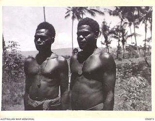 PRAED POINT, NEW BRITAIN, 1945-09-15. TOMARO AND TURLURA, TWO NATIVES WHO WORKED ON THE EMPLACEMENT OF AUSTRALIAN 6-INCH GUNS AT PRAED POINT, PROUDLY WEAR AGAIN, THE IDENTIFICATION DISCS GIVEN TO ..