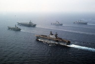 Ships from four nations sail in formation during the NATO Southern Region exercise DRAGON HAMMER '90. In the foreground is the amphibious assault ship USS SAIPAN (LHA 2). In the background are, from left: the Spanish aircraft carrier SPS PRINCIPE DE ASTURIAS (R-11), the nuclear-powered aircraft carrier USS DWIGHT D. EISENHOWER (CVN 69), the Italian light aircraft carrier ITS GIUSEPPE GARIBALDI (C-551), and the British light aircraft carrier HMS INVINCIBLE (R-05)