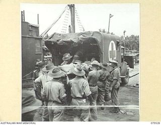 ORO BAY, NEW GUINEA. 1943-07. LOADING A PATIENT INTO AN AMBULANCE OF THE 10TH FIELD AMBULANCE FOR TRANSPORT TO THE UNIT MAIN DRESSING STATION