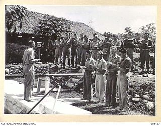 LAE AREA, NEW GUINEA. 1945-07-29. THE CONGREGATION SINGING HYMNS DURING THE BAPTISMAL SERVICE FOR PRIVATE I. LOHNEYER, 2/7 ADVANCED WORKSHOP (2), CONDUCTED BY CHAPLAIN A.H. ORR (1), AT HEADQUARTERS ..
