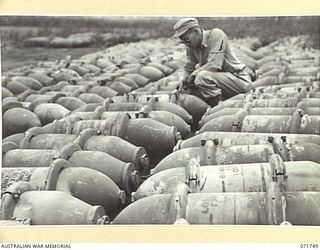 LAE, NEW GUINEA, 1944-03-26. 2ND LIEUTENANT N. T. GRAHAM, 337TH UNITED STATES ORDNANCE DEPOT CHECKS BOMBS AT THE UNIT DUMP