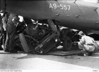 Tadji, New Guinea. 1945-01-21. A badly smashed Australian Army jeep under the tail of A9-557, a DAP Beaufort bomber aircraft operated by No 100 Squadron RAAF. This aircraft returned from a strike ..
