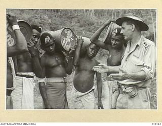 1943-06-28. NEW GUINEA. WAU-MUBO AREA. NATIVE CARRIERS LEAVE FOR FORWARD AREAS. ON ONE OF THE TRACKS THEY RECEIVE INSTRUCTIONS FROM LIEUT. K. ALLEN, OF INVERELL, N.S.W. (NEGATIVE BY G. SHORT)