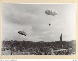 ULEBILUM RIDGE, YAMIL SECTOR, NEW GUINEA, 1945-07-08. PARACHUTES FALLING ON BILL DROPPING ZONE STRIP WHERE THEY ARE UNFASTENED BY ARMY PERSONNEL AND TRANSPORTED TO THE ARMY SERVICE CORPS STORE BY ..