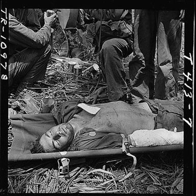 Wounded Pfc. Robison in stretcher on Guam after receiving blood plasma.