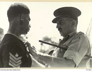 LAE, NEW GUINEA. 1944-04-01. MAJOR GENERAL B.M. MORRIS, DSO, (1), GENERAL OFFICER COMMANDING AUSTRALIAN NEW GUINEA ADMINISTRATIVE UNIT, PRESENTS THE BRITISH EMPIRE MEDAL TO SERGEANT MAJOR ARWESOR, ..