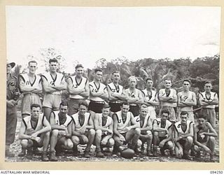 Group portrait of members of the 29/46 Infantry Battalion football team on the ground before the start of play. They played against the 22 Infantry Battalion team, another 4 Infantry Brigade unit, ..