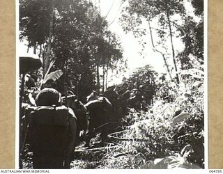UBERI AREA, NEW GUINEA. 1943-12-19. NATIVE CARRIERS AND MEMBERS OF THE 2/9TH INFANTRY BATTALION AT GOLDIES CROSSING NEAR OWERS' CORNER PLAYING EXTRAS DURING THE FILMING OF THE FINAL SEQUENCES OF ..
