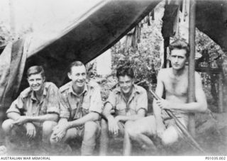 Four spotters from the New Guinea Air Warning Wireless Company (NGAWW) sitting by their tent. Identified, left to right: R Pardy; S Savage; B P (Spud) Murphy MM, and C Turnbull MM. Note the strain ..