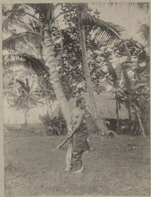 Samoan man standing near a traditional house, Samoa, approximately 1895