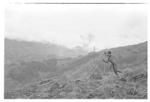 Man tilling the soil with two long digging sticks, slopes and ridges in the background 2