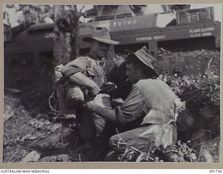 WEWAK AREA, NEW GUINEA, 1945-05-10. MEN OF 2/4 INFANTRY BATTALION MAKING ADJUSTMENTS TO EQUIPMENT BEFORE ADVANCING AGAINST ENTRENCHED JAPANESE FORCES IN CAVES, TUNNELS AND PILLBOXES. THEY ARE BEING ..