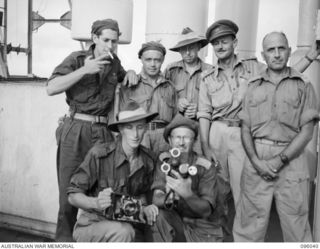 AT SEA OFF RABAUL, NEW BRITAIN. 1945-09-06. THE MILITARY HISTORY FIELD TEAM, WHICH COVERED THE JAPANESE SURRENDER CEREMONY ON BOARD THE AIRCRAFT CARRIER HMS GLORY, FACE THE CAMERA, AFTER ..