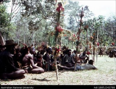 Men seated behind decorated fence