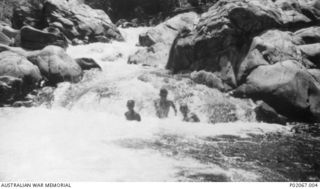Goodenough Island, New Guinea. c. 1944. Three members of a Beaufort bomber crew bathing in a river at the base of a small waterfall near Vivigani Airfield. Left to right: 422062 Flying Officer (FO) ..