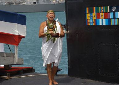 Brother Franklin Pao stands next to the sail of the Los Angeles Class Attack Submarine USS HONOLULU (SSN 718) as he performs the Hawaiian water blessing during a farewell ceremony, at Pearl Harbor, Hawaii (HI)