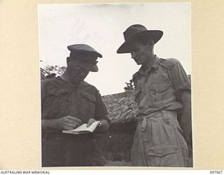 MAPRIK, NEW GUINEA. 1945-10-03. CAPTAIN M. VERSO, MEDICAL OFFICER (1) DISCUSSING MEDICAL SUPPLIES WITH SERGEANT J.S. MARLOW (2) AT AUSTRALIAN NEW GUINEA ADMINISTRATIVE UNIT HEADQUARTERS