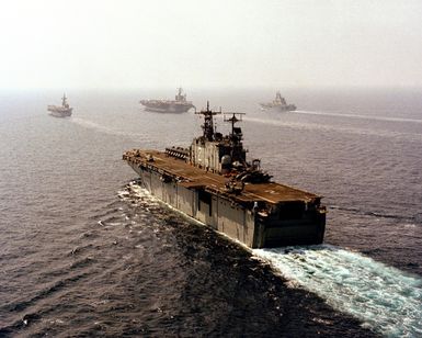 A port quarter view of the amphibious assault ship USS SAIPAN (LHA 2) underway during the NATO Southern Region exercise DRAGON HAMMER '90. In the background are, from left: the Spanish aircraft carrier SPS PRINCIPE DE ASTURIAS (R-11) the nuclear-powered aircraft carrier USS DWIGHT D. EISENHOWER (CVN 69 and the Italian light aircraft carrier ITS GIUSEPPE GARIBALDI (C-551)