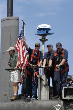 US Navy (USN) Commander (CDR) Kevin Brenton, Commanding Officer, USS SAN FRANCISCO (SSN 711), waves farewell to the crowd on the pier, as his Los Angeles Class Attack Submarine gets underway from Naval Base Guam. The SAN FRANCISCO is heading for its new homeport at Bremerton, Washington (WA)