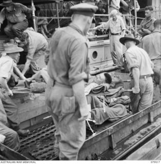 LAE, NEW GUINEA. 1943-11. PERSONNEL OF THE 10TH FIELD AMBULANCE TRANSFERRING PATIENTS FROM THE HOSPITAL SHIP, SS "STRADBROKE II" TO AN ARMY AMPHIBIOUS DUKW FOR TRANSPORTATION TO THE AIRSTRIP FOR ..