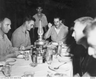 NEW GEORGIA, SOLOMON ISLANDS. 1943-03. DINNER AT KENNEDY'S SEGI COASTWATCHERS STATION (ZGJ5) . LEFT TO RIGHT LIEUTENANT CARSON, UNITED STATES NAVY RESERVE; CAPTAIN BOYD, UNITED STATES MARINE CORPS; ..