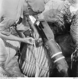 HANSA BAY, NEW GUINEA. 1944-07-10. NX115529 LIEUTENANT R.A. DICKSON, 8TH FIELD COMPANY, ROYAL AUSTRALIAN ENGINEERS, REMOVING THE INSTANTANEOUS FUSE OF A BOOBY TRAPPED JAPANESE AERIAL BOMB AT AN ..