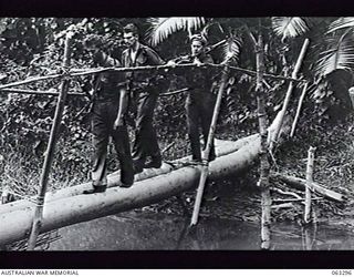 FAITA, NEW GUINEA. 1944-01-07. MEMBERS OF 2/2ND CAVALRY (COMMANDO) SQUADRON RETURNING TO HEADQUARTERS FROM A PATROL IN THE RAMU VALLEY THROUGH JAPANESE HELD TERRITORY CROSS AN IMPROVISED TWO-LOG ..